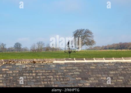 Metall-Wetterfahne von Rebhuhn auf Scheunendach mit blau Himmel und grünes Gras im Hintergrund Stockfoto