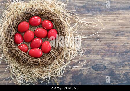 Traditionelle rot bemalte Eier auf Strohdekor für griechisch-orthodoxe Osterfeiern gelegt. Stockbild. Stockfoto