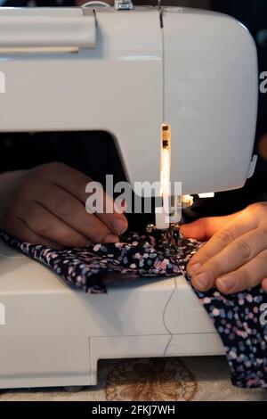 Eine Frau, die Kleidung mit einer Nähmaschine näht und repariert Zu Hause Stockfoto