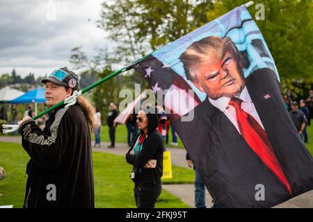 Portland, Oregon. Mai 2021. Ein Mann mit der Flagge des ehemaligen US-Präsidenten Donald Trump sieht zu, wie Menschen bei einer „Mayday 2a“-Kundgebung für Waffenrechte, die von den Proud Boys, einer rechtsextremen Gruppe, am 1. Mai 2021 in Salem, Oregon, organisiert wurde, Reden halten. Die Gruppe, die über lokale Kapitel in den USA verfügt, wird von Strafverfolgungsbehörden wegen ihrer Rolle bei den Unruhen im US-Kapitol am 6. Januar 2021 überprüft. (Foto: Gaspard Le dem/Sipa USA) Quelle: SIPA USA/Alamy Live News Stockfoto