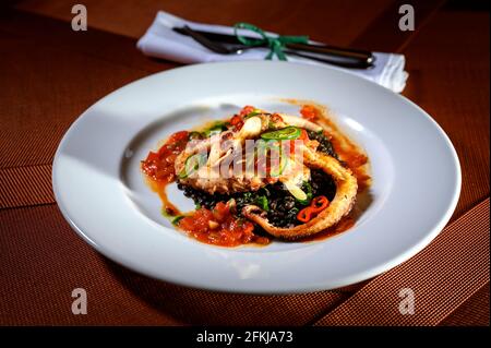 Geröstete Tintenfisch-Tentakeln mit etwas Gemüse in einem feinen Restaurant. Stockfoto