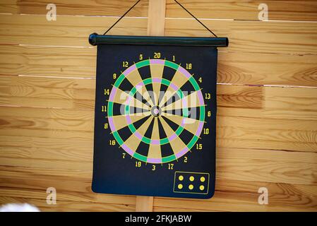 Darts mit schwarzen und gelben Sektoren hängen auf einem hölzernen Steh auf Stockfoto