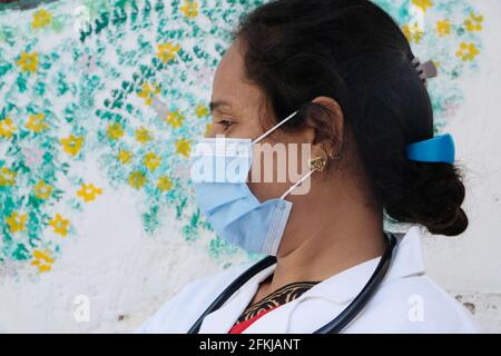 Eine indische Ärztin, die eine medizinische Gesichtsmaske trägt Und Laborkittel mit einem Stethoskop um den Hals Schule während Covid-19 Stockfoto
