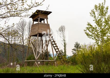 Hölzerner Huntsman-Hochsitz am Waldrand Vor einer Wiese mit hellem Hintergrund Stockfoto