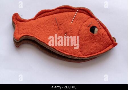 Altmodisches orangefarbenes Nadelkissen in der Form eines Flache Fische mit Nadeln und Nadeln Stockfoto