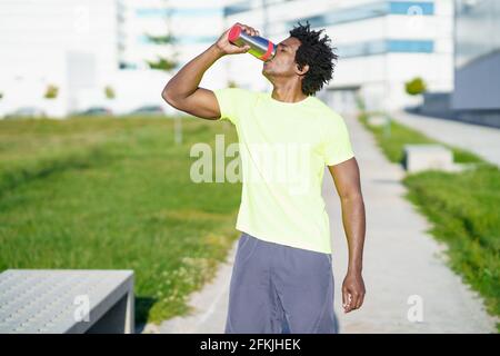 Schwarzer Mann trinkt während der Übung. Der Läufer nimmt eine Trinkpause ein. Stockfoto