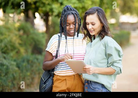 Zwei multiethnische Frauen beraten sich auf einem digitalen Tablet. Stockfoto