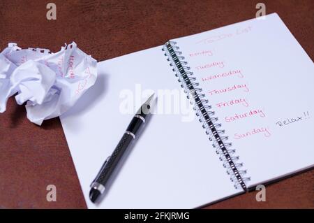 To-Do-Liste für eine Woche. Offenes Notizbuch mit schwarzer Abdeckung auf braunem Hintergrund. . Großes Textfeld Stockfoto