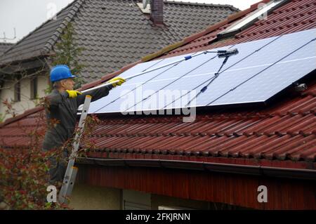 Reinigung von Solarmodulen. Ein Mann auf einer Leiter reinigt und wäscht eine Photovoltaikanlage. Stockfoto