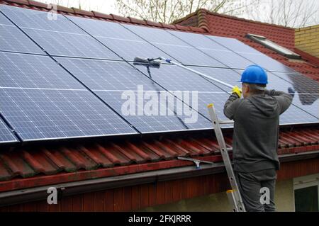 Reinigung von Solarmodulen. Ein Mann auf einer Leiter reinigt und wäscht eine Photovoltaikanlage. Stockfoto