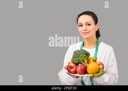 Gesunde Ernährung. Ernährungsberater mit Obst und Gemüse für die Ernährung in den Händen über grauen Hintergrund Stockfoto