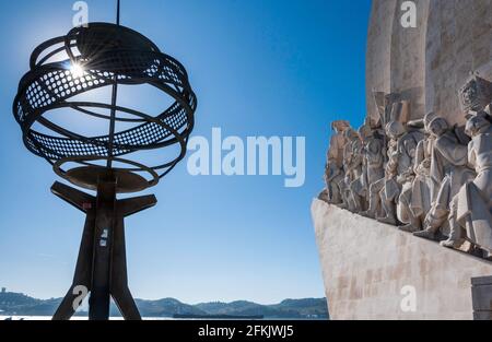 Skulptur einer Armillarsphäre (Weltmaschine) im Stadtteil Belem von Lissabon. Hintergrundbeleuchtetes Foto zur blauen Stunde, mit einem Abschnitt des Monument to Th Stockfoto