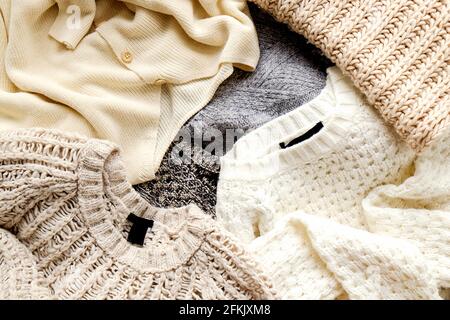 Strickpullover in warmen Pastelltönen mit verschiedenen Strickmustern in einem chaotischen Stapel, der deutlich sichtbar ist. Stilvolle Herbst-/Wintersaison Stockfoto