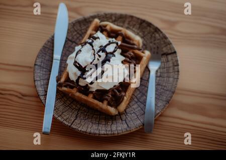 Ein Schuss belgischer Waffeln mit Schokolade und Creme Auf einem Holzteller Stockfoto