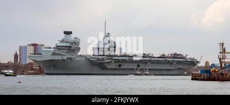 Portsmouth, England, Großbritannien. 2021. HMS Queen Elizabeth ein Flugzeugträger mit begleiteten Schleppern verlässt Portsmouth Harbour an der farbenfrohen Wohnung vorbei Stockfoto