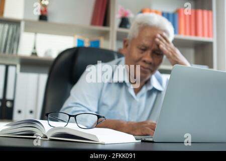 Happy Senior Asian mit dem Laptop für die Berechnung und notieren Sie sich die täglichen Ausgaben. Konzept von Lifestyle, Lernen und Finanzgeschäft Stockfoto