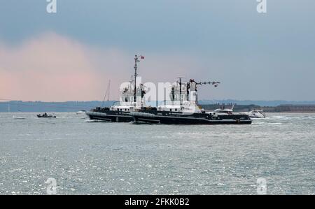 Portsmouth, England, Großbritannien. 2021. Zwei Schlepper mit Schleppleinen an HMS Queen Elizabeth, die im Solent vor Portsmouth, Großbritannien, arbeitet Stockfoto