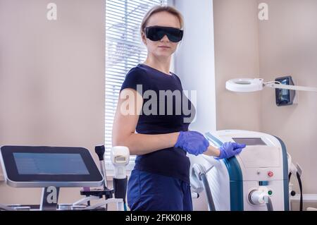 Der Kosmetologe steht in der Nähe des Laser- und HF-Hebegeräts. Hardware-Kosmetologie Stockfoto