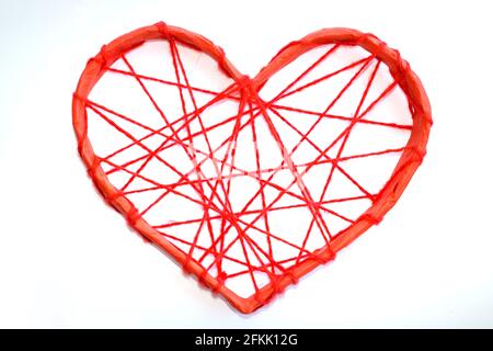 Ein Papierherz, das mit roten Fäden gebunden ist. Herz auf weißem Hintergrund. Stockfoto
