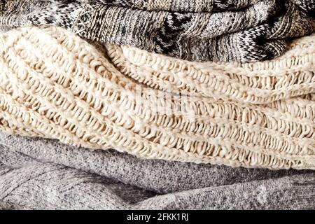 Strickpullover in warmen Pastelltönen mit verschiedenen Strickmustern in einem chaotischen Stapel, der deutlich sichtbar ist. Stilvolle Herbst-/Wintersaison Stockfoto