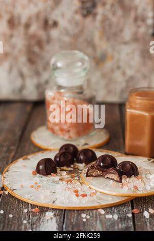 Hausgemachte Schokoladenbonbons mit gesalzener Karamellsauce auf Vintage-Hintergrund Stockfoto