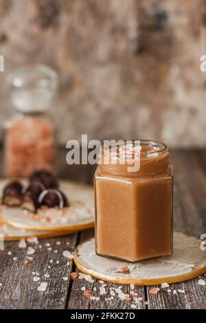 Hausgemachte gesalzene Karamellsauce im Glas auf Vintage-Hintergrund Stockfoto