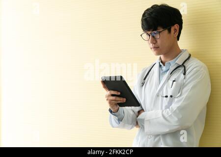 Junge asiatische Ärzte mit Tabletten, um Daten und Informationen für die gesundheitliche Untersuchung von Patienten zu überprüfen. Konzept der digitalen, Technologie und Kommunikation Stockfoto