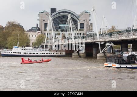 Ein Boot mit der Thames Rocket Rib fährt in der Nähe der Charing Cross Station und der Golden Jubilee Footbridge und der Hungerford Bridge, Waterloo, London, England, Großbritannien Stockfoto