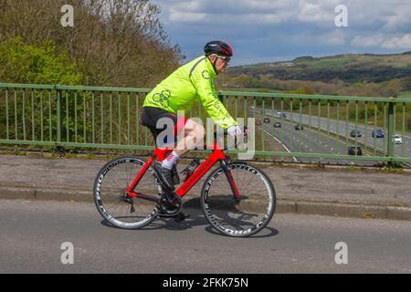 Älterer Radler mit Boardman Carbon-Sport-Rennrad auf der Landstraße über die Autobahnbrücke im ländlichen Lancashire, Großbritannien Stockfoto