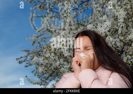 Hübsche junge Brünette Frau mit einer starken Allergie-Reaktion im Frühling, Niesen, Stuffiness, Gesundheitskonzept Stockfoto