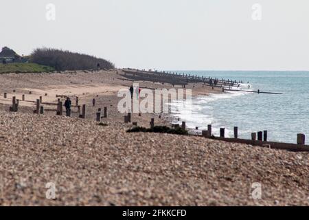 Nicht erkennbare Menschen, die an einem leeren Strand in West Sussex, Großbritannien, spazieren Stockfoto