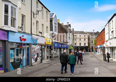 Bridgend, Wales - April 2021: Menschen, die die Caroline Street, eine Fußgängerzone im Einkaufszentrum der Stadt, entlang gehen. Stockfoto