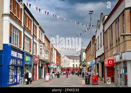 Bridgend, Wales - April 2021: Menschen, die die Adare Street, eine Fußgängerzone im Einkaufszentrum der Stadt, entlang gehen. Stockfoto