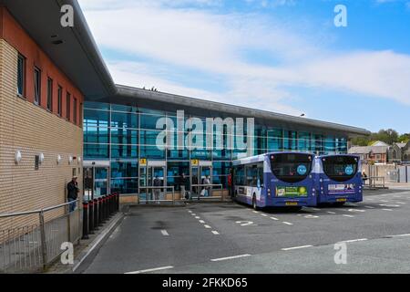 Bridgend, Wales - April 2021: Busse parken im Busbahnhof im Stadtzentrum von Bridgend. Die Leute warten darauf, in einen der Busse zu steigen. Stockfoto