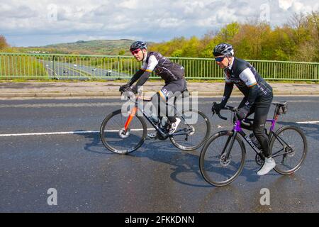 Ein Radsportler fährt auf einer Landstraße über die Autobahnbrücke im ländlichen Lancashire, Großbritannien, mit einem Cannondale Carbon-Rennrad Stockfoto