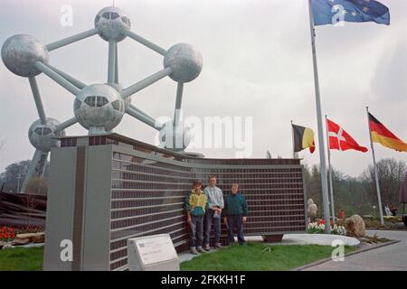 Drei junge Männer posieren im Mini-Europe, Gebäude der Europäischen Kommission, wenige Monate nach seiner Einweihung, am 1990. April, im Hintergrund das Atomium, Brüssel, Belgien Stockfoto