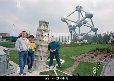Drei junge Jungen posieren im Mini-Europe, Schiefer Turm in Pisa, wenige Monate nach seiner Einweihung, am 1990. April, im Hintergrund das Atomium, Brüssel, Belgien Stockfoto