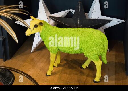 London, Großbritannien - 2020. Dezember, Weihnachtsdekoration. Kunststoff gelb-grüne Schafe vor dem Hintergrund von weißen und schwarzen Sternen im Liberty-Shop Stockfoto