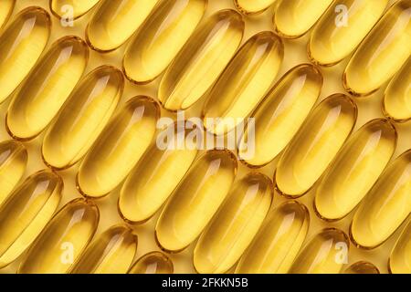 Fischöl-Kapseln in einer Reihe, Omega 3 Softgels auf gelbem geometrischen Hintergrund. Stockfoto