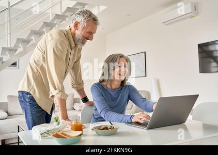 Glückliches Paar mittleren Alters, das Spaß mit Laptop-Computer zu Hause hat. Stockfoto