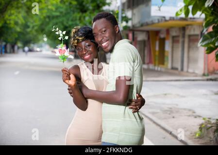 Romantisches Angebot zu heiraten. Ein Mann überrascht seine Freundin in der Stadt. Vorschlag zum Valentinstag. Junger Mann, der eine Blume für g gibt Stockfoto