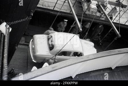 In den 1950er Jahren wurde an den Docks ein Auto der Austin Canbridge A40 auf den Rumpf eines Bootes, Irland, gehoben. Stockfoto