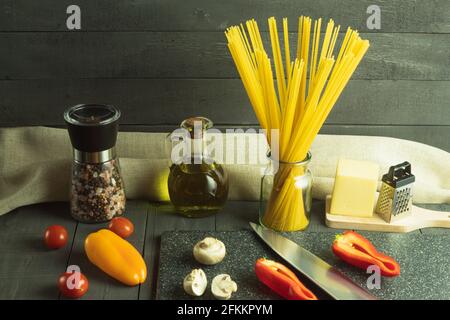 Rohe, trockene italienische Spaghetti und frisches Gemüse. Spaghetti Pasta, Gemüse und Gewürze und Käse auf einem Holztisch. Hintergrund mit Platz für Text Stockfoto