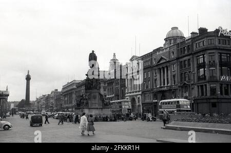 1950er Jahre, historisch, Dublin, Irland, Blick auf die O'Connell Street, der im Vordergrund das Denkmal für Daniel O'Connell zeigt, einen irischen nationalistischen Führer aus dem 19. Jahrhundert, nach dem die Straße 1924 benannt wurde. Allgemeine Aktivität und auf dem Bild ist ein Paar Doppeldecker-Busse zu sehen. Stockfoto