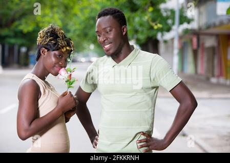 Romantisches Angebot zu heiraten. Ein Mann überrascht seine Freundin in der Stadt. Vorschlag zum Valentinstag. Junger Mann, der eine Blume für g gibt Stockfoto