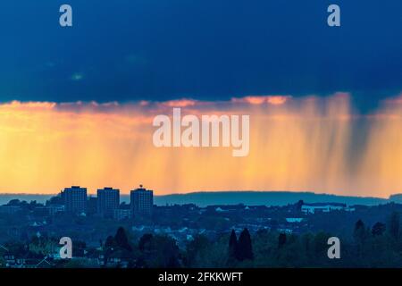 Brierley Hill, West Midlands, Großbritannien. Mai 2021. Ein orangefarbener Himmel und starke Regenschauer fallen über Wohnblöcke in Brierley Hill im Black Country, West Midlands, wenn die Sonne untergeht. Die Wetterprognose für den Montag am Bankfeiertag ist starker Regen und starker Wind im ganzen Land. Peter Lopeman/Alamy Live News Stockfoto