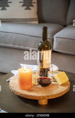 Eine Käseplatte mit Wein, Käse, Crackern und einer brennenden Kerze in einem Hotelzimmer. Stockfoto
