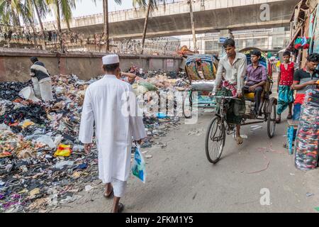 DHAKA, BANGLADESCH - 21. NOVEMBER 2016: Haufen Müll und Rikschas in der Siddique Bazar Straße im Zentrum von Dhaka, Bangladesch Stockfoto