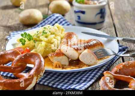 Gebratene bayerische Würstchen, sogenannte Wollwurst, eine Spezialität ähnlich der deutschen Kalbswurst, aber ohne Hülle, serviert mit hausgemachtem Kartoffelsalat Stockfoto