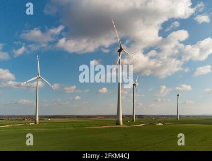 Luftaufnahme von großen Windenergieanlagen mit Rotorblättern im Feld vor blauem Himmel und weißen Wolken. Alternative Energie. Windpark erzeugt grüne Energie. Stockfoto